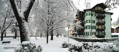 a building covered in snow in a park at Residence Hotel Gasser in Bressanone