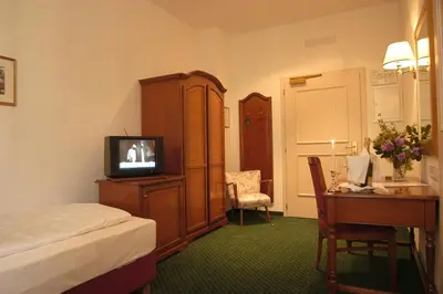 a hotel room with a bed and a television and a desk at Residence Hotel Gasser in Bressanone