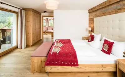 a bedroom with a bed with a red blanket on it at Almhof Hotel Call in San Vigilio Di Marebbe
