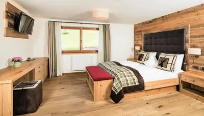 a bedroom with a large bed and a television at Almhof Hotel Call in San Vigilio Di Marebbe