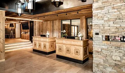 a room with a stone wall and a vanity with a mirror at Almhof Hotel Call in San Vigilio Di Marebbe