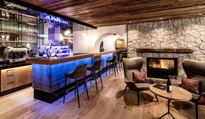 a bar in a restaurant with a fireplace at Almhof Hotel Call in San Vigilio Di Marebbe