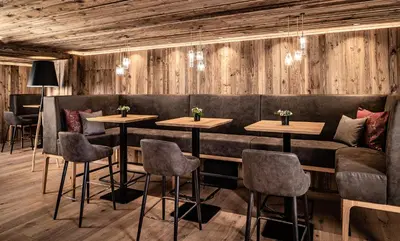 a restaurant with wooden walls and tables and chairs at Almhof Hotel Call in San Vigilio Di Marebbe