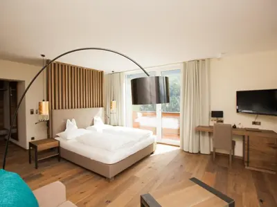 a bedroom with a bed and a desk and a television at Hotel Zirmerhof & Residence in Rifiano