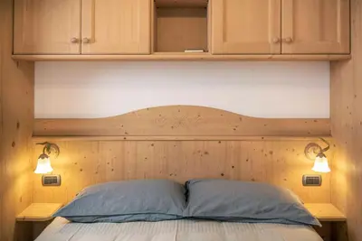 a bed with a wooden headboard and two pillows at Casa Rododendro - Cavalese Dolomites in Cavalese