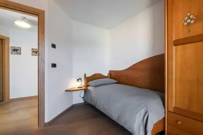 a bedroom with a bed with a wooden headboard at Casa Rododendro - Cavalese Dolomites in Cavalese