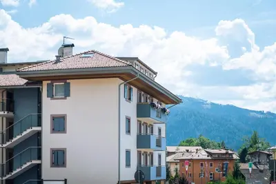 a white building with a mountain in the background at Casa Rododendro - Cavalese Dolomites in Cavalese