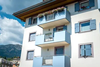 a building with blue shutters and flowers on the balconies at Casa Rododendro - Cavalese Dolomites in Cavalese