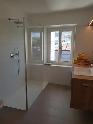 a bathroom with a shower and a sink and windows at Hager Apartment 3 in Merano