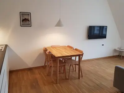 a dining room table with chairs and a tv on a wall at Hager Apartment 3 in Merano