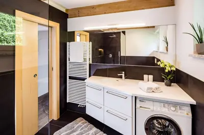 a bathroom with a sink and a washing machine at Haus Sauvignon in Cortaccia