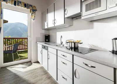 a kitchen with white cabinets and a view of a balcony at Haus Sauvignon in Cortaccia