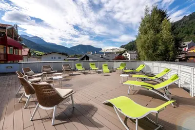 a group of chairs and tables on a balcony at Hotel Relais Orsingher in Fiera di Primiero