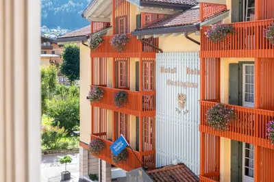 an apartment building with orange balconies and plants on it at Hotel Relais Orsingher in Fiera di Primiero