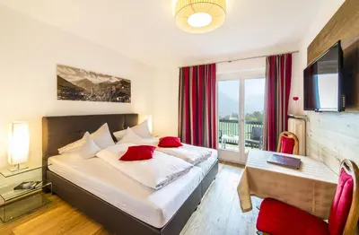 a hotel room with a bed and a desk and a window at Hotel Pension Verdorfer in Merano