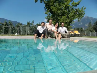 a group of people sitting next to a swimming pool at Hotel Pension Verdorfer in Merano
