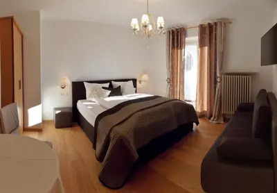 a bedroom with a large bed and a chandelier at Hotel Pension Verdorfer in Merano