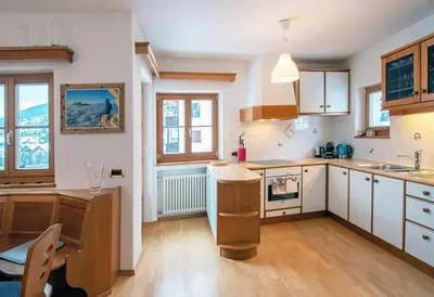 a kitchen with white cabinets and wooden floors and windows at Mountain Living Apartment Idylia in Ortisei