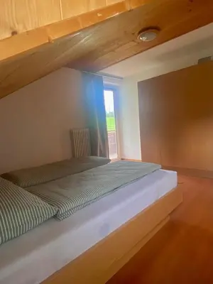 a large bed in a room with a window at Schönhuberhof Apartment Panoramablick in Brunico