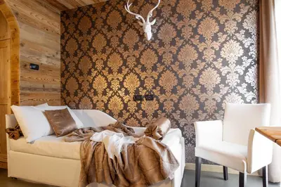 a bedroom with a bed and two chairs and a wall at Hotel Astoria in Fiera di Primiero