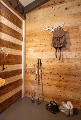 a room with a wooden wall with a camera and a backpack at Hotel Astoria in Fiera di Primiero