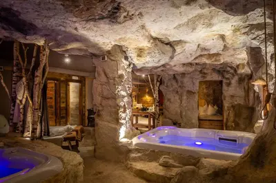 a bathroom in a cave with a bathtub in a stone wall at Hotel Astoria in Fiera di Primiero