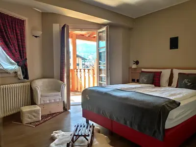 a bedroom with a large bed and a balcony at Hotel Astoria in Fiera di Primiero