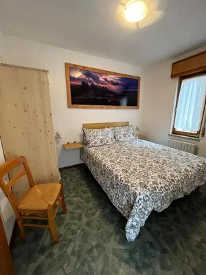 a bedroom with a bed and a chair at Dolomitihouse AUNER in Fiera di Primiero