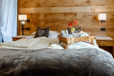 a bedroom with two beds and a table with flowers on it at Hotel Menardi in Cortina dʼAmpezzo