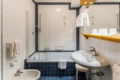 a bathroom with a sink and a bath tub with a sink at Hotel Menardi in Cortina dʼAmpezzo