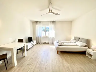 a white living room with a couch and a table at Bright studio apartment with free private parking in Merano