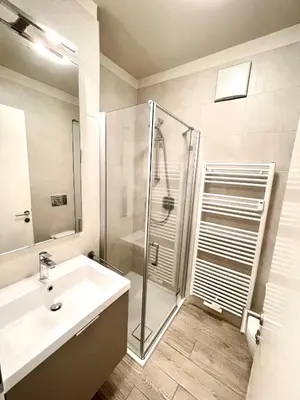 a white bathroom with a shower and a sink at Bright studio apartment with free private parking in Merano