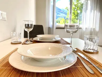 a table with a plate and wine glasses on it at Bright studio apartment with free private parking in Merano