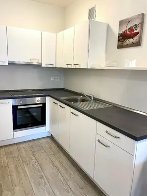 a kitchen with white cabinets and a sink at Bright studio apartment with free private parking in Merano