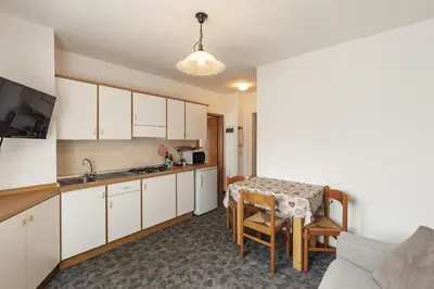 a kitchen with white cabinets and a table with chairs at Dolomitihouse AVET in Fiera di Primiero