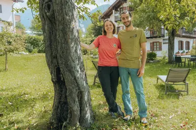 a man and a woman standing next to a tree at Dolomitihouse AVET in Fiera di Primiero