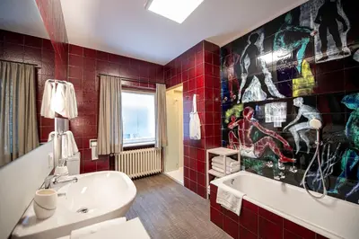 a bathroom with red tiled walls and a white tub at Apartment Murata in Ortisei