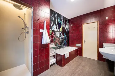 a red tiled bathroom with a sink and a shower at Apartment Murata in Ortisei