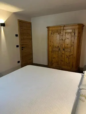 a bedroom with a white bed and wooden cabinets at Remina Dolomiti house in Tonadico