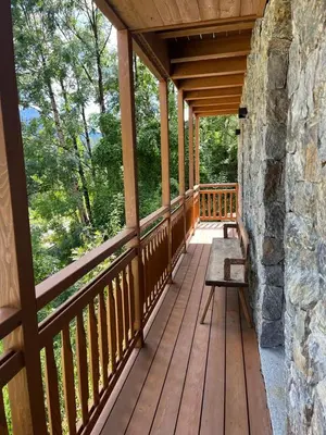 a wooden porch of a cabin with a stone wall at Remina Dolomiti house in Tonadico
