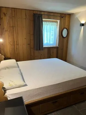 a large bed in a room with a clock on the wall at Remina Dolomiti house in Tonadico