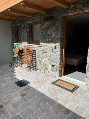 a stone building with chairs and a couch on a patio at Remina Dolomiti house in Tonadico