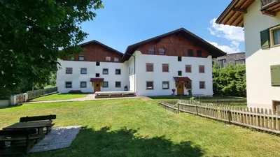 a large white building with a wooden fence at Schlernwohnung in Seis am Schlern in Siusi