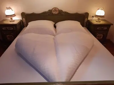 a bed with two pillows and two night stands at Schlernwohnung in Seis am Schlern in Siusi