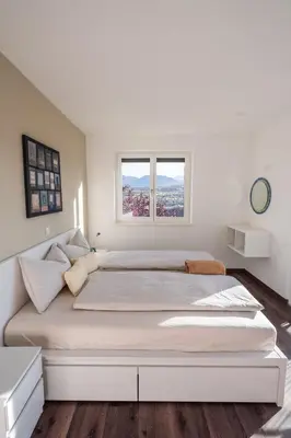 a large bed in a white room with two windows at Pia´s Bleibe in Caldaro