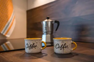 two coffee mugs sitting on a table with a coffee pot at Pia´s Bleibe in Caldaro