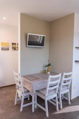 a dining room table with chairs and a television on the wall at Pia´s Bleibe in Caldaro