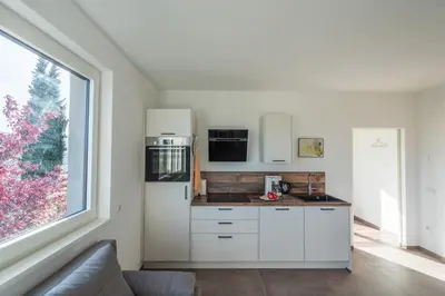 a kitchen with white cabinets and a large window at Pia´s Bleibe in Caldaro