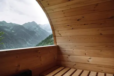a wooden sauna with a window with mountains in the background at Mountain house Ebner in Selva dei Molini