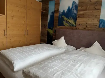 a bedroom with a white bed with wooden cabinets at A Sosta in Selva di Val Gardena